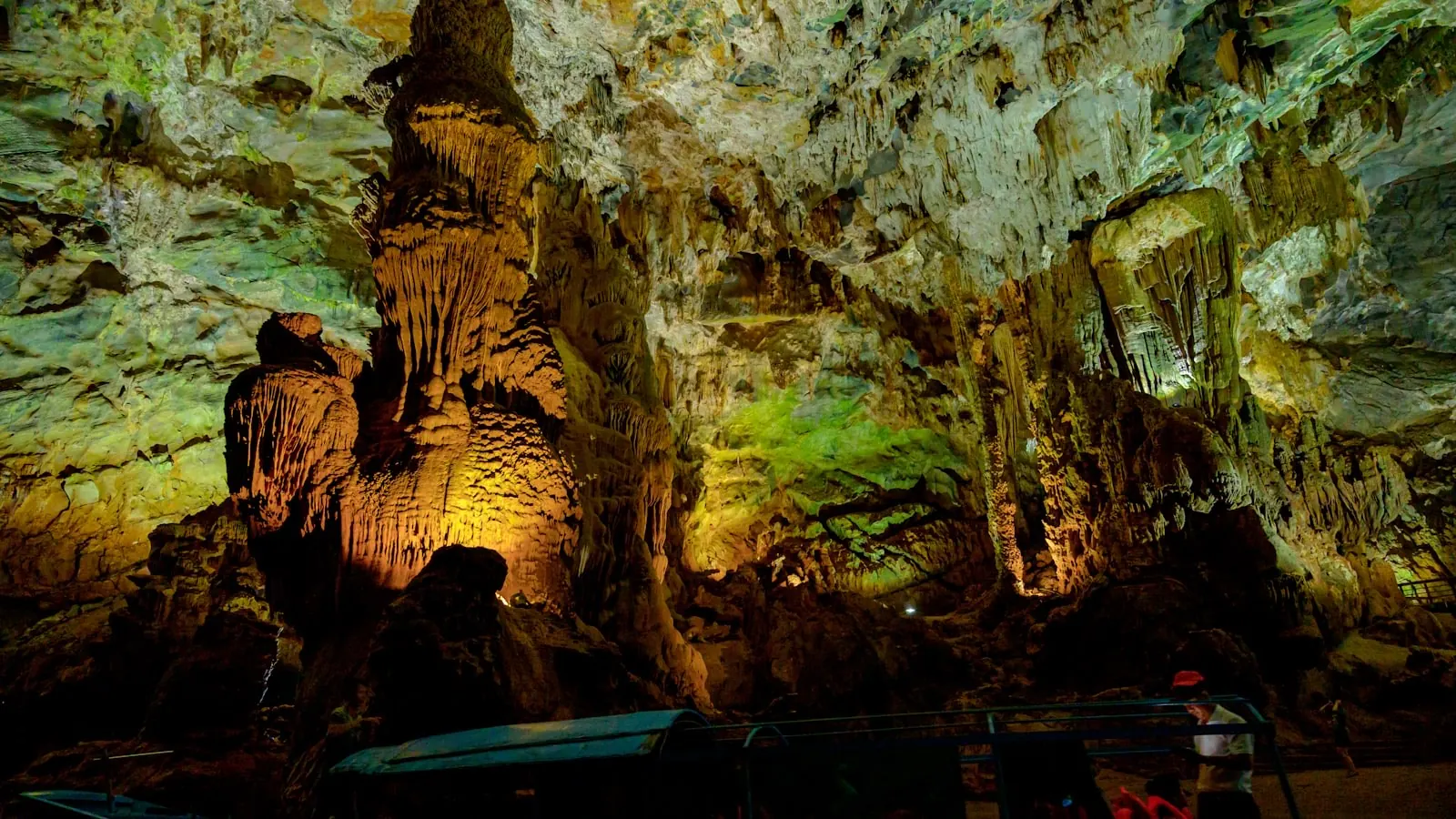 Lòng động Phong Nha với khối thạch nhũ lớn được chiếu sáng vàng và xanh, du khách đứng trên lối đi phía dưới