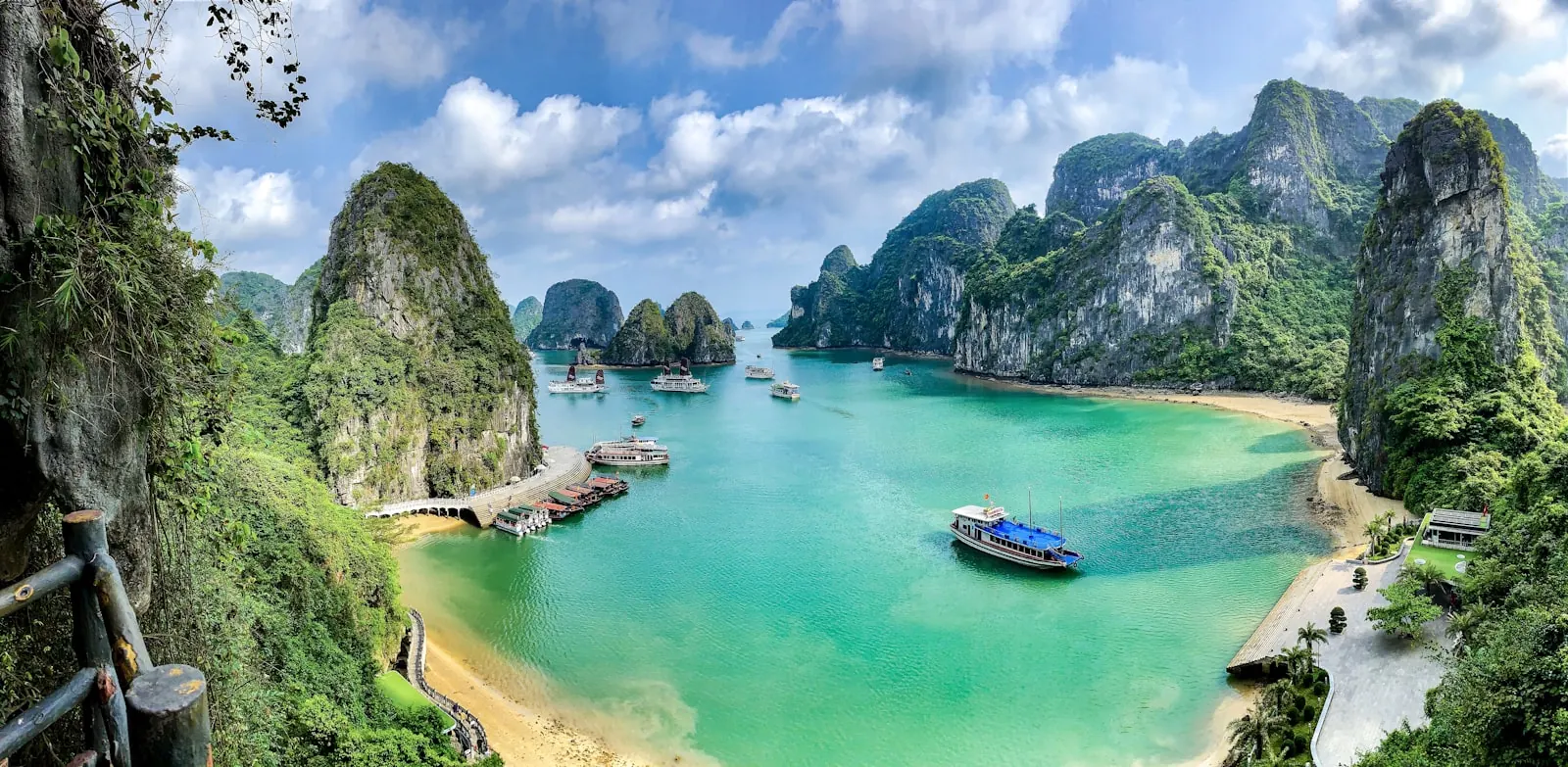 Vịnh Hạ Long nhìn từ trên cao với các đảo đá vôi phủ cây xanh, nước biển màu ngọc bích và những chiếc tàu du lịch neo gần bờ