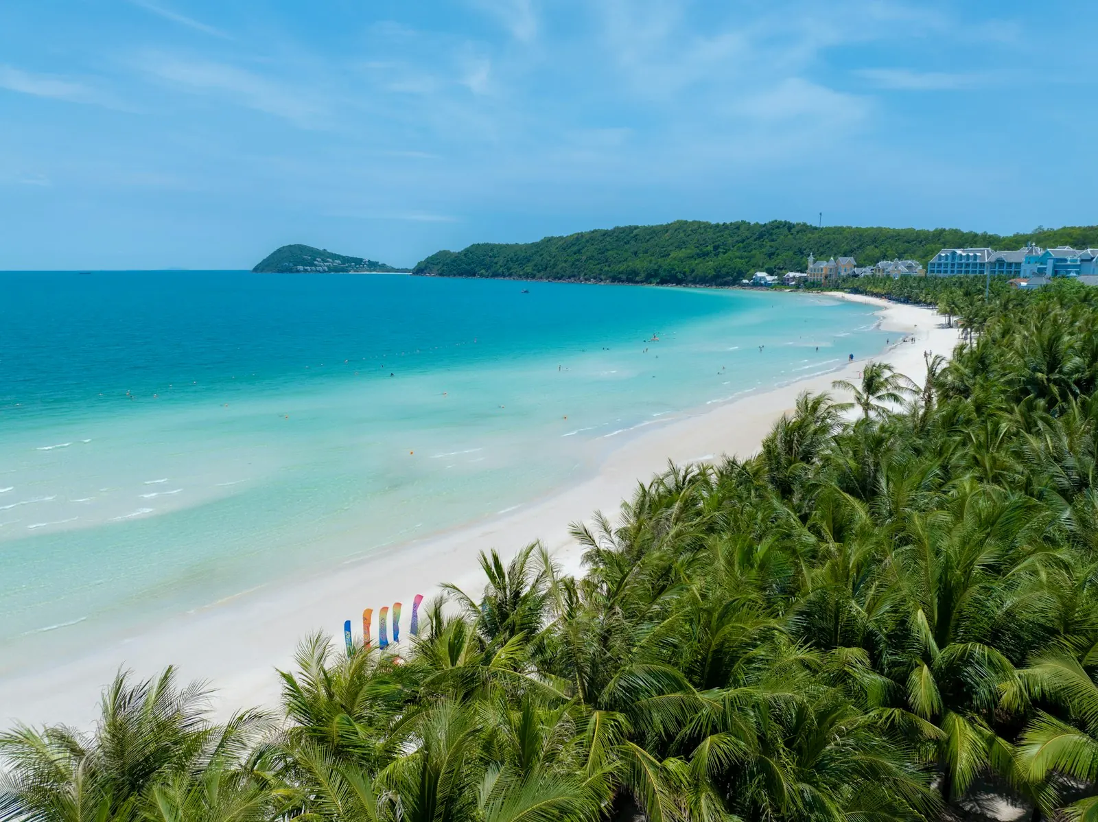 Bãi biển cong hình lưỡi liềm ở Phú Quốc nhìn từ trên cao, cát trắng viền nước biển màu ngọc, rừng dừa và khu nghỉ dưỡng phía sau